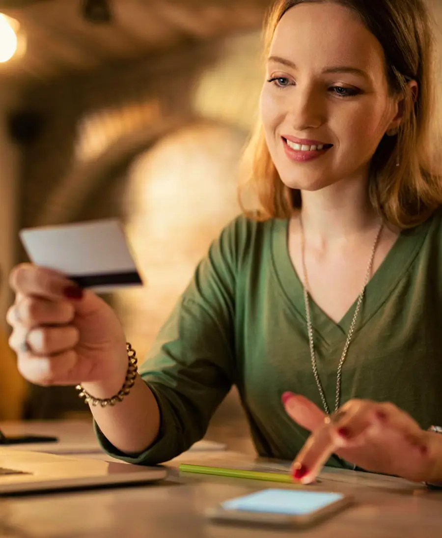 Woman holding a credit card, ready to make an online purchase, representing a secure checkout process.